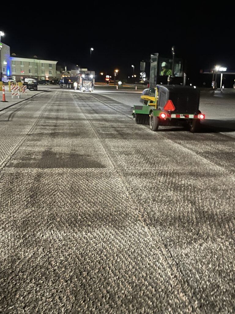 Asphalt paving machinery working on a commercial parking lot at night, showcasing K&K Contracting's expertise in asphalt repair and resurfacing.