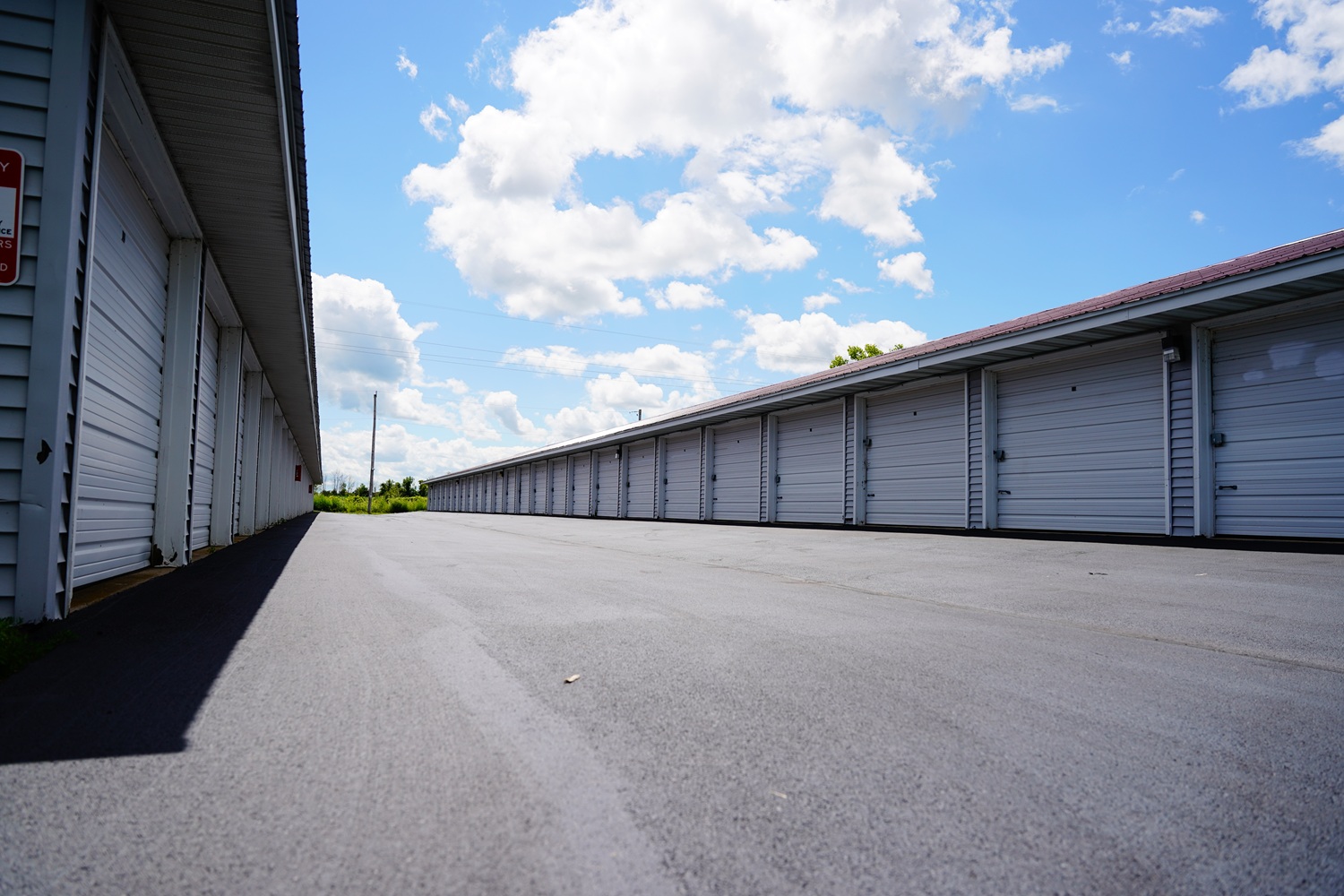 Asphalt-paved storage facility with multiple garage doors under a bright blue sky, showcasing durable pavement solutions by K&K Contracting in Caseyville, IL.