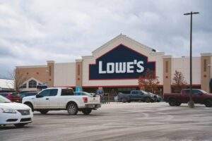 Retail center asphalt parking lot in summer, featuring a large storefront, smooth paved surface, marked parking spaces, and vehicles parked throughout the lot.
