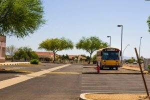 Yellow school bus parked in a school parking lot with freshly painted lines, emphasizing back-to-school pavement safety