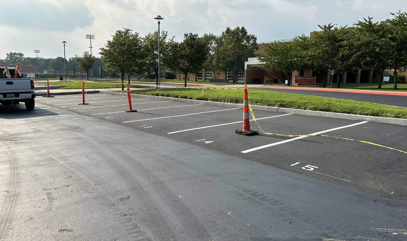Newly repaved school parking lot with fresh line striping and numbered spaces